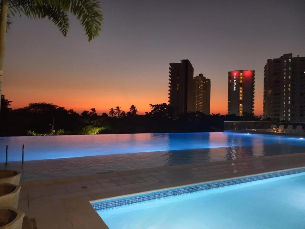 a swimming pool with a city skyline at night at Apartamento con vista al mar Santa Marta in Santa Marta