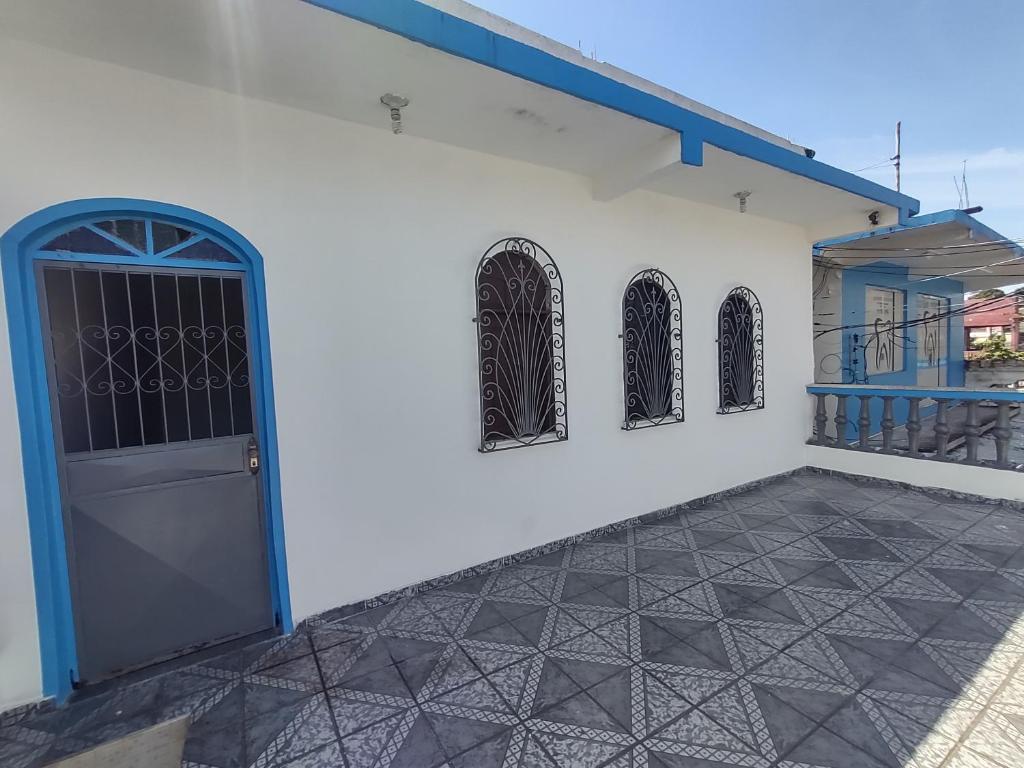 ein weißes Gebäude mit einer blauen Tür und Fenstern in der Unterkunft Casa grande em área central, bem iluminada e vent. in Manaus