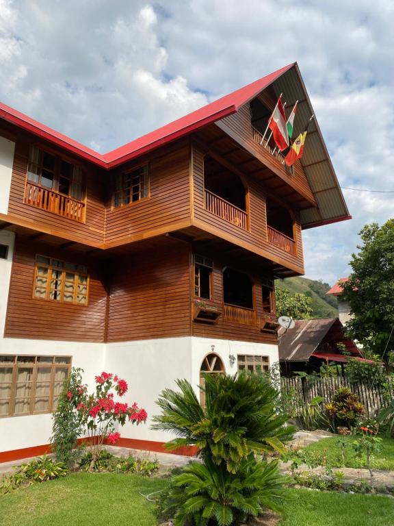 a house with a balcony with a flag on it at HAUS KÖHEL HOSPEDAJE POZUZO in Pozuzo