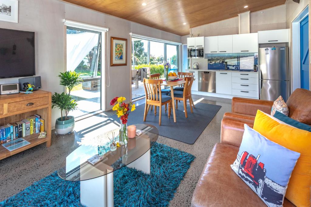 a living room with a couch and a table at Hahei Beach Bach. in Hahei