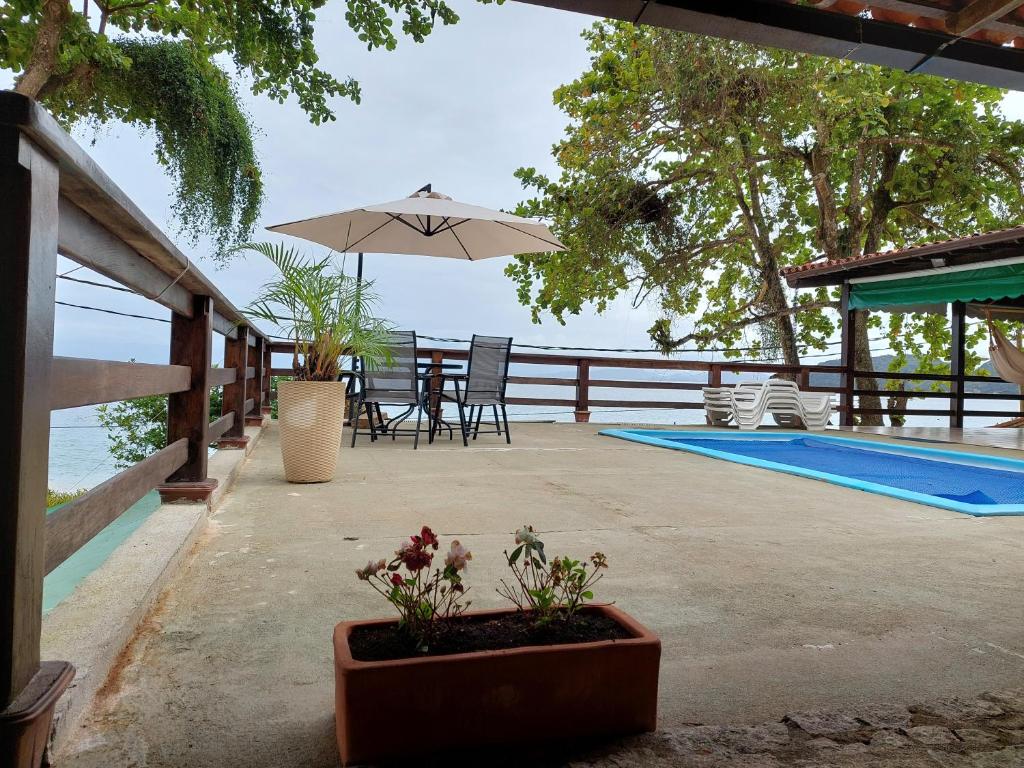 a patio with a table and an umbrella next to a pool at Espaço Villa Ará in Praia de Araçatiba