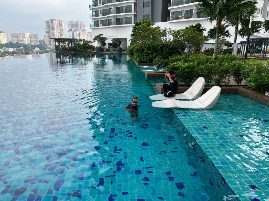 2 personas sentadas en las tumbonas de una piscina en Datum Jelatek MHQ NAF Perfect, Relaxing, Sky Ring Bridge en Kampong Datok Keramat
