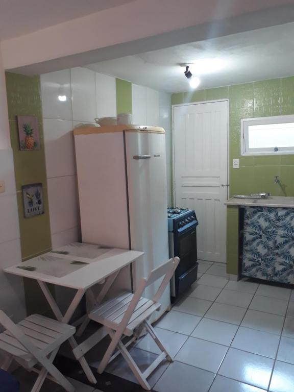 eine Küche mit einem Tisch und Stühlen sowie einem Kühlschrank in der Unterkunft Chalés sal da terra/Chalé in Caraguatatuba