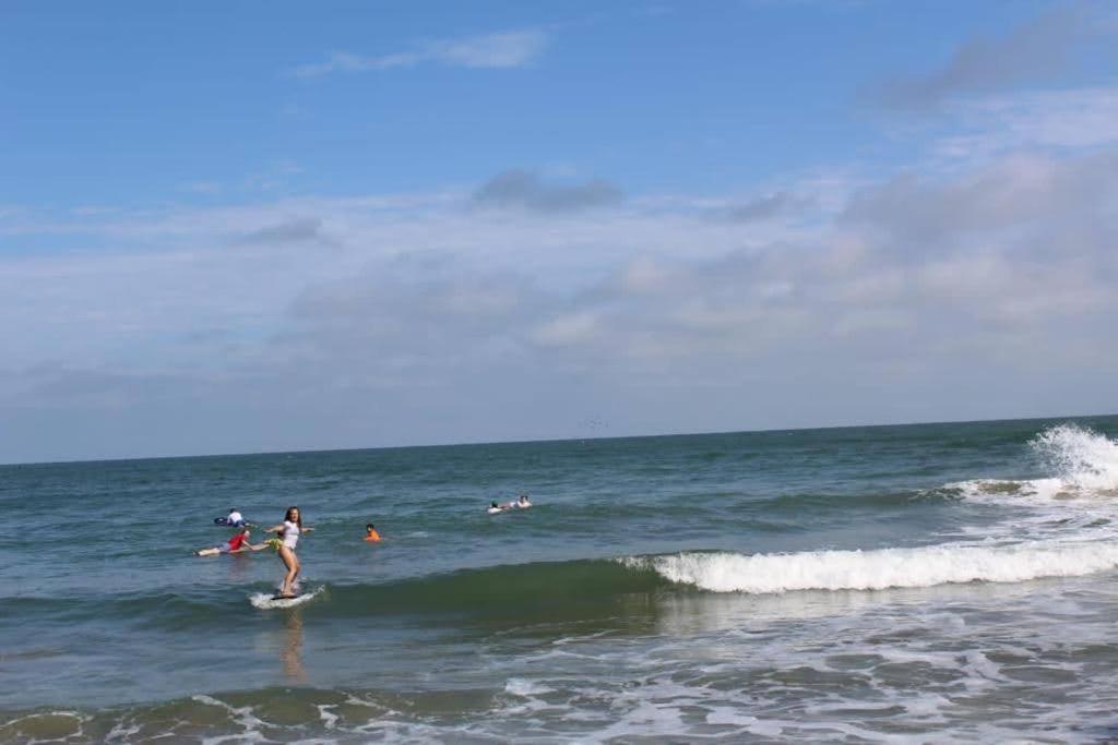 un grupo de personas en tablas de surf en el océano en Un Dia Boutique Resort, en Playas