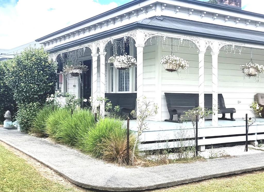 a white house with a bench on a porch at Pheasant Lodge in Paparoa