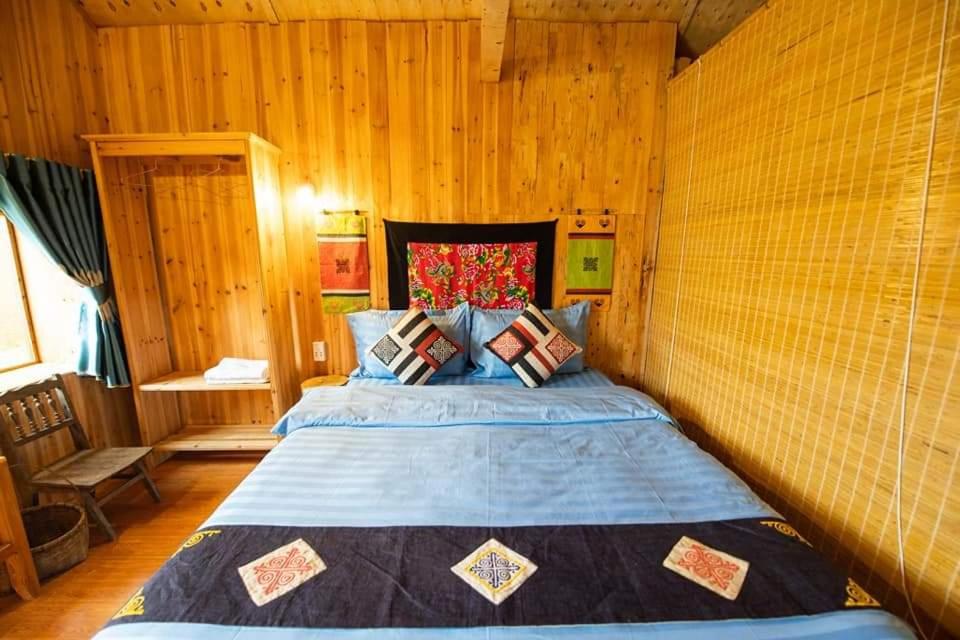 Quản Bạ的住宿－Hong Thu Homestay & Bungalow，卧室配有一张床铺,位于带木墙的房间内