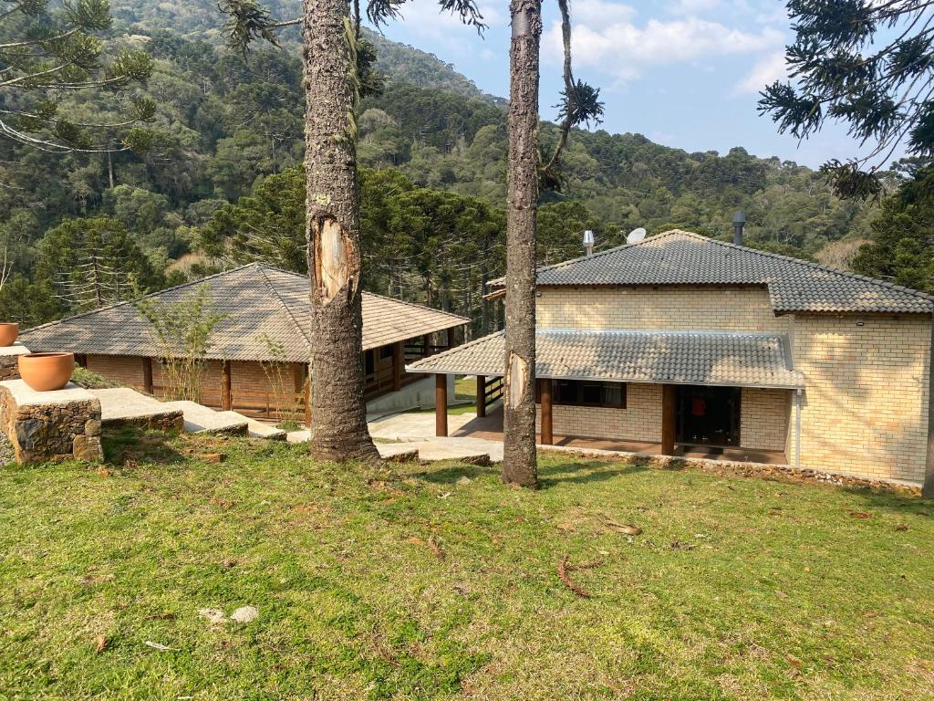 a house with trees in a field next to a building at Pousada Rural Encanto do Riacho in Bom Jardim da Serra