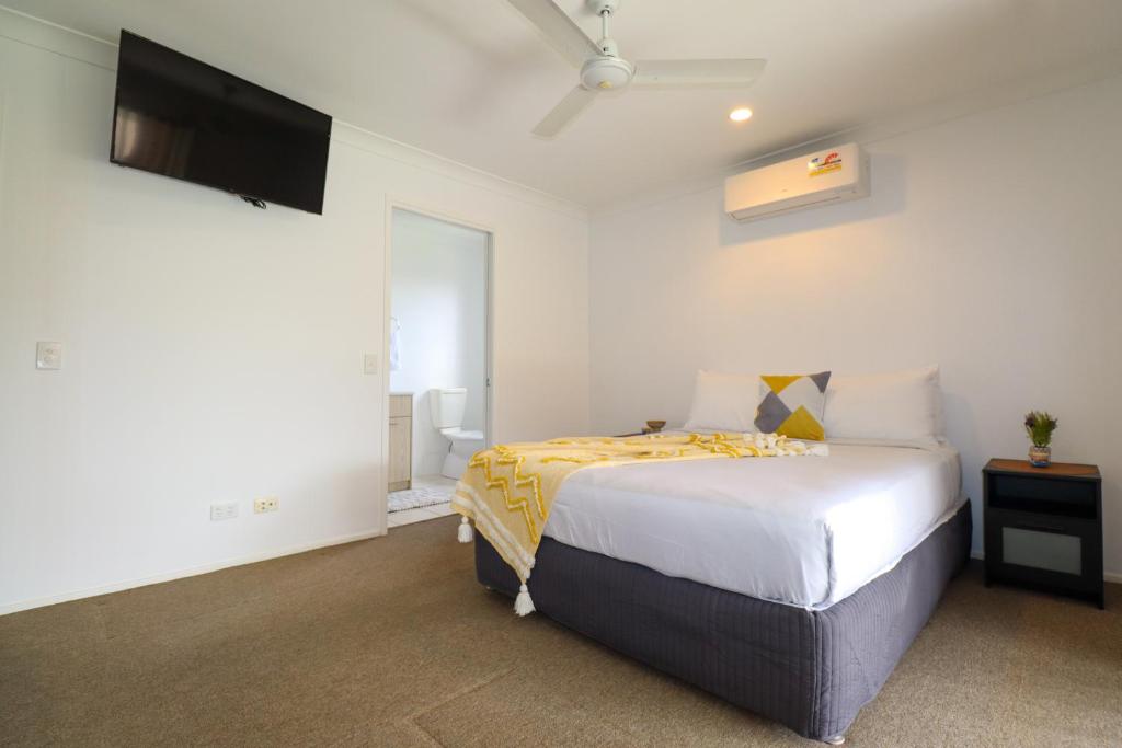 a bedroom with a bed and a flat screen tv at BLK Stays Guest House Deluxe Units Bellmere 