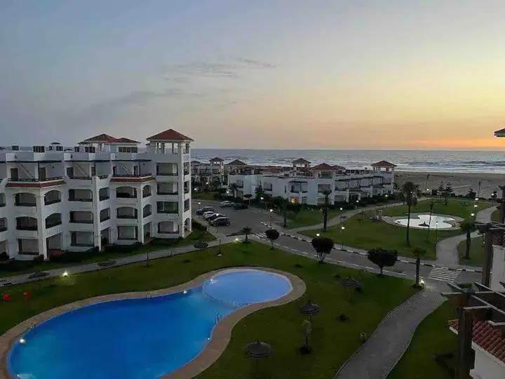 a view of a resort with a pool and the ocean at Appartement pied dans l eau à Residence Beralmar in Asilah