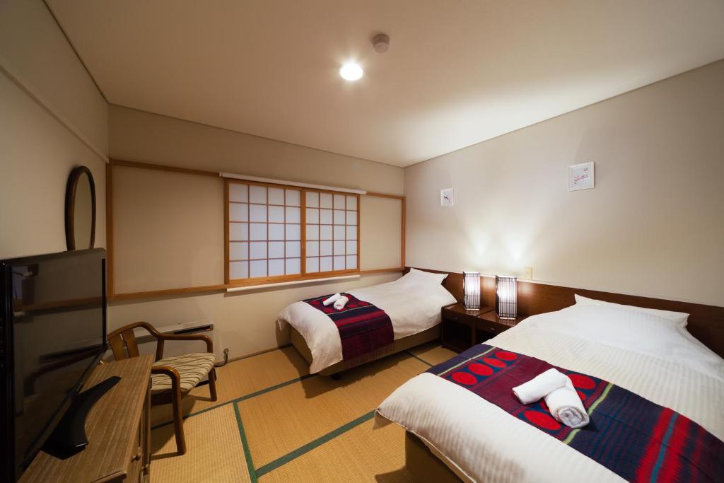a hotel room with two beds and a television at Luna Lodge in Hakuba