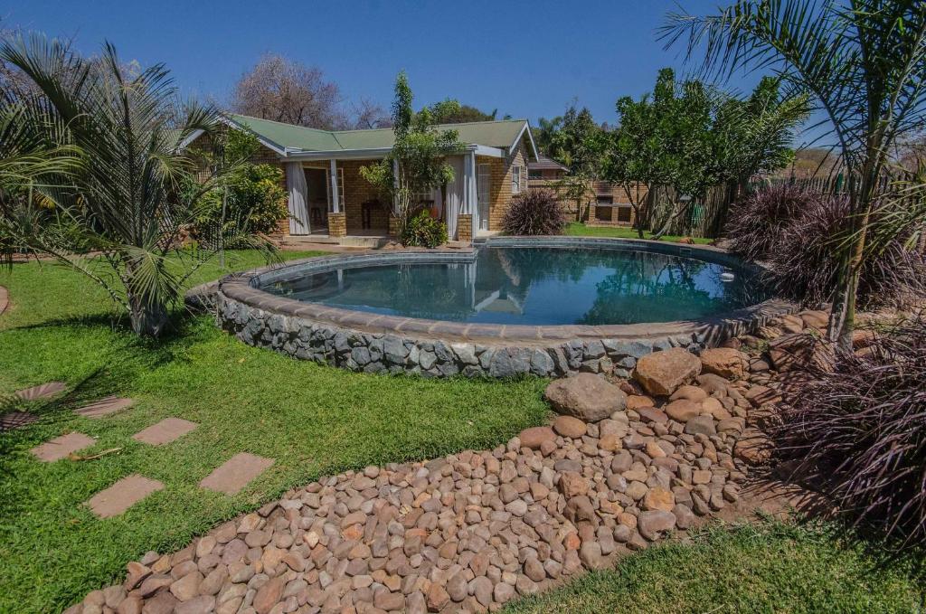 a backyard with a swimming pool and a rock wall at Chobe River Cottages in Kasane