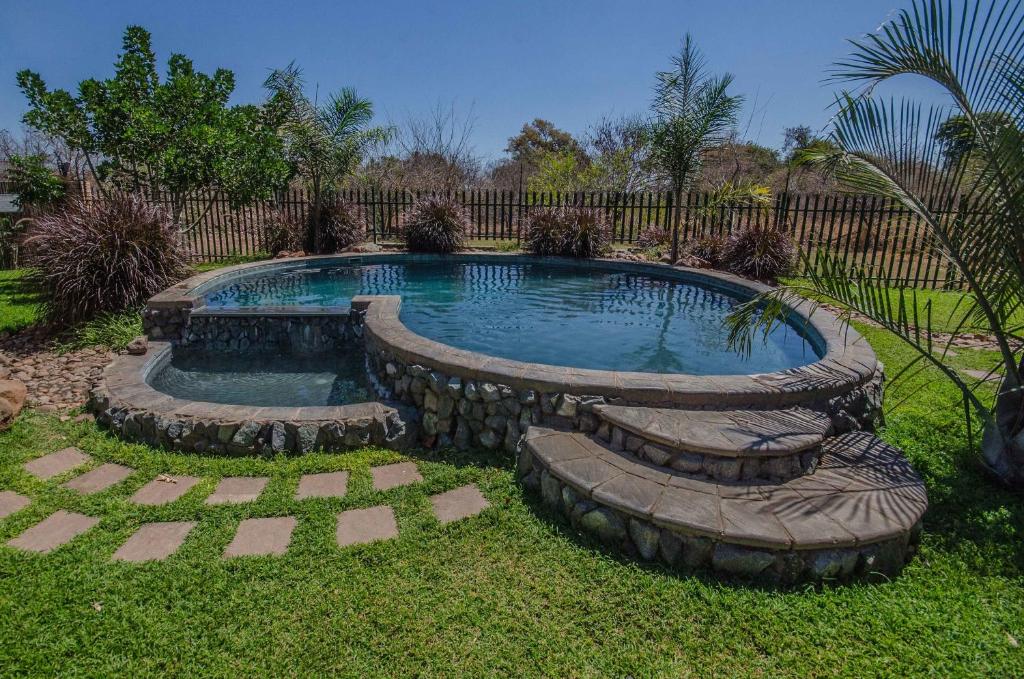 a swimming pool in a yard with rocks around it at Chobe River Cottages in Kasane