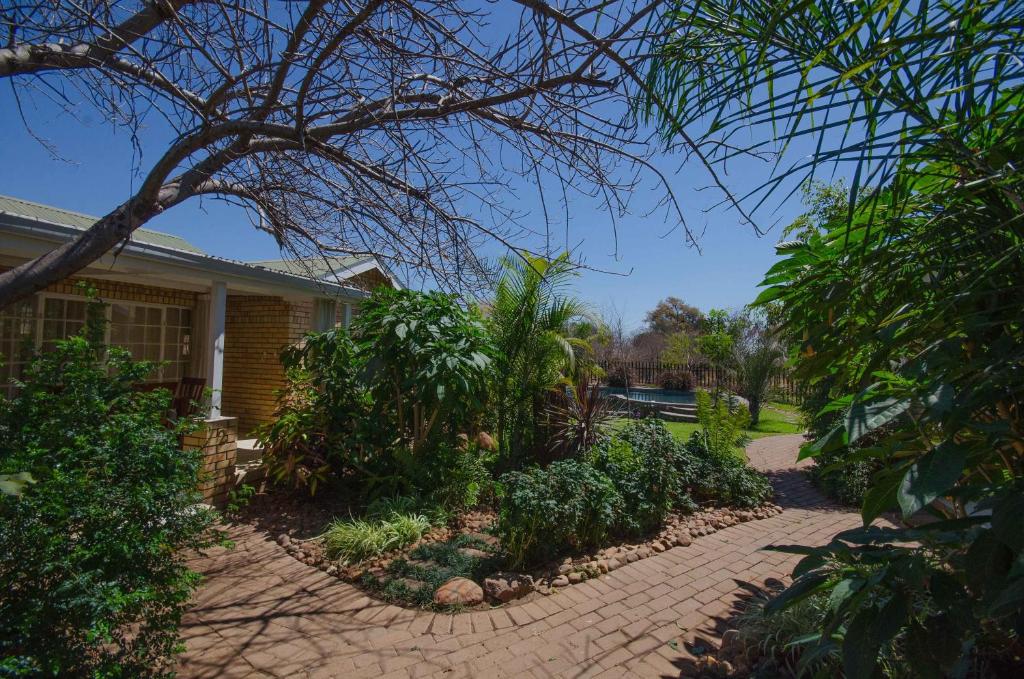 a house with a brick driveway in front of a yard at Chobe River Cottages in Kasane