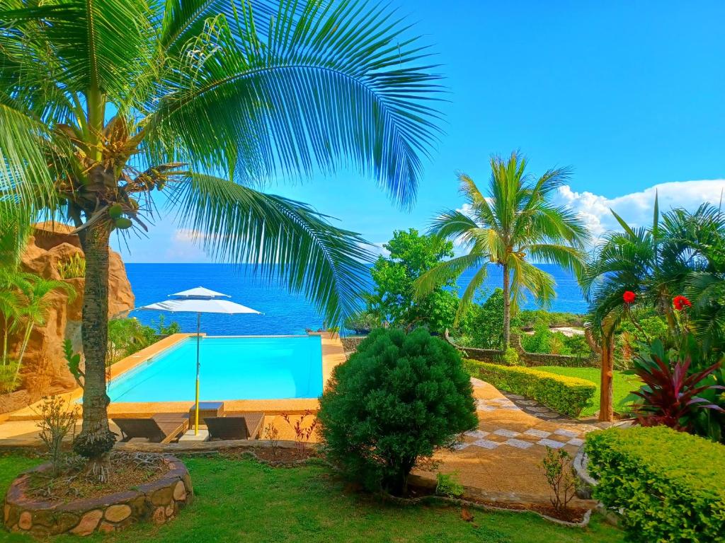 een resort met een zwembad en palmbomen en de oceaan bij Villa Camotes in Camotes Islands
