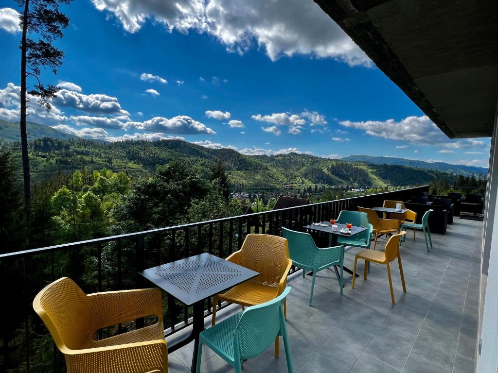 a balcony with tables and chairs and mountains at Карпатський Затишок in Slavske