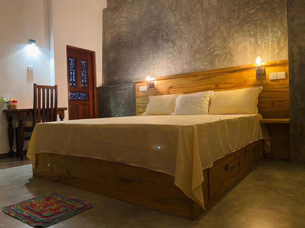1 dormitorio con 1 cama grande y cabecero de madera en The Cozy Nest en Hikkaduwa