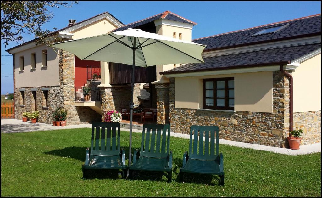 two chairs and an umbrella in front of a house at Apartamentos Rurales Casanova in Tapia de Casariego