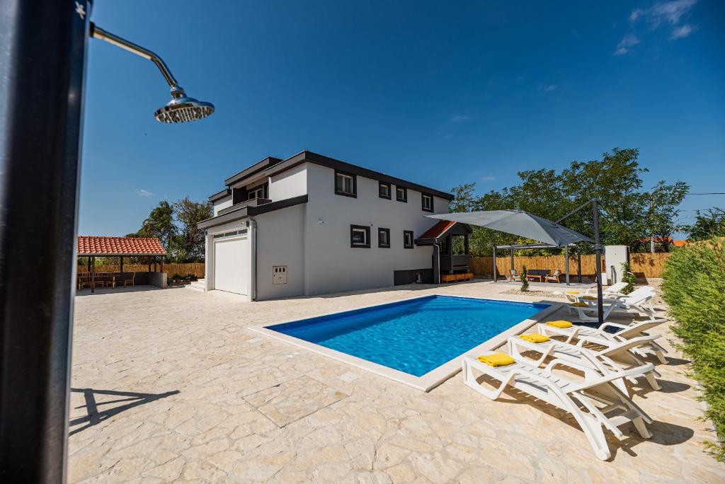 a swimming pool with chairs and a house at Villa Heaven in Donji Zemunik
