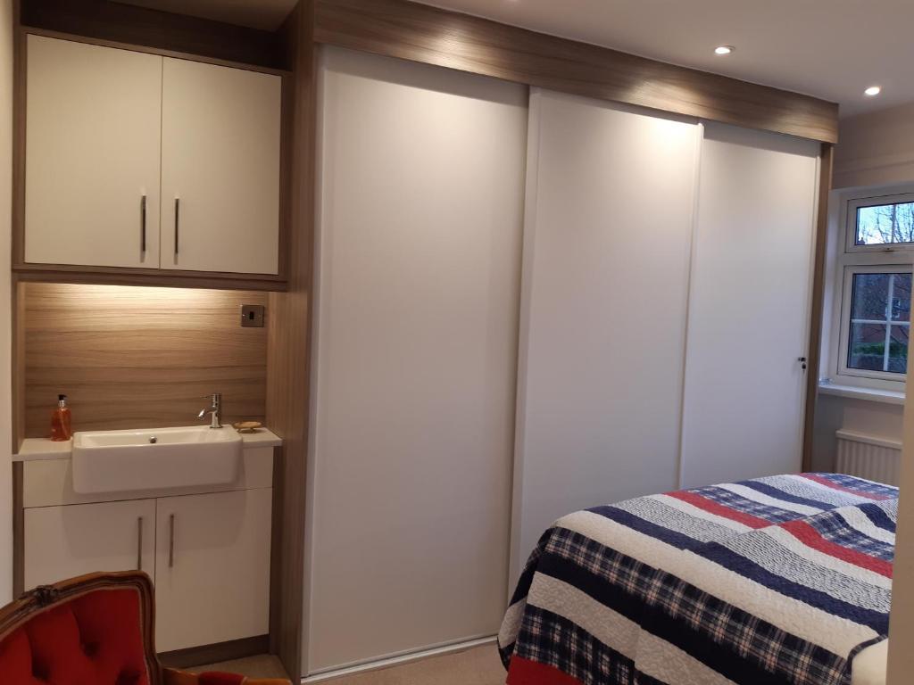 een slaapkamer met witte kasten, een wastafel en een bed bij Smitten House 4 Bedroom RHYL in Rhyl