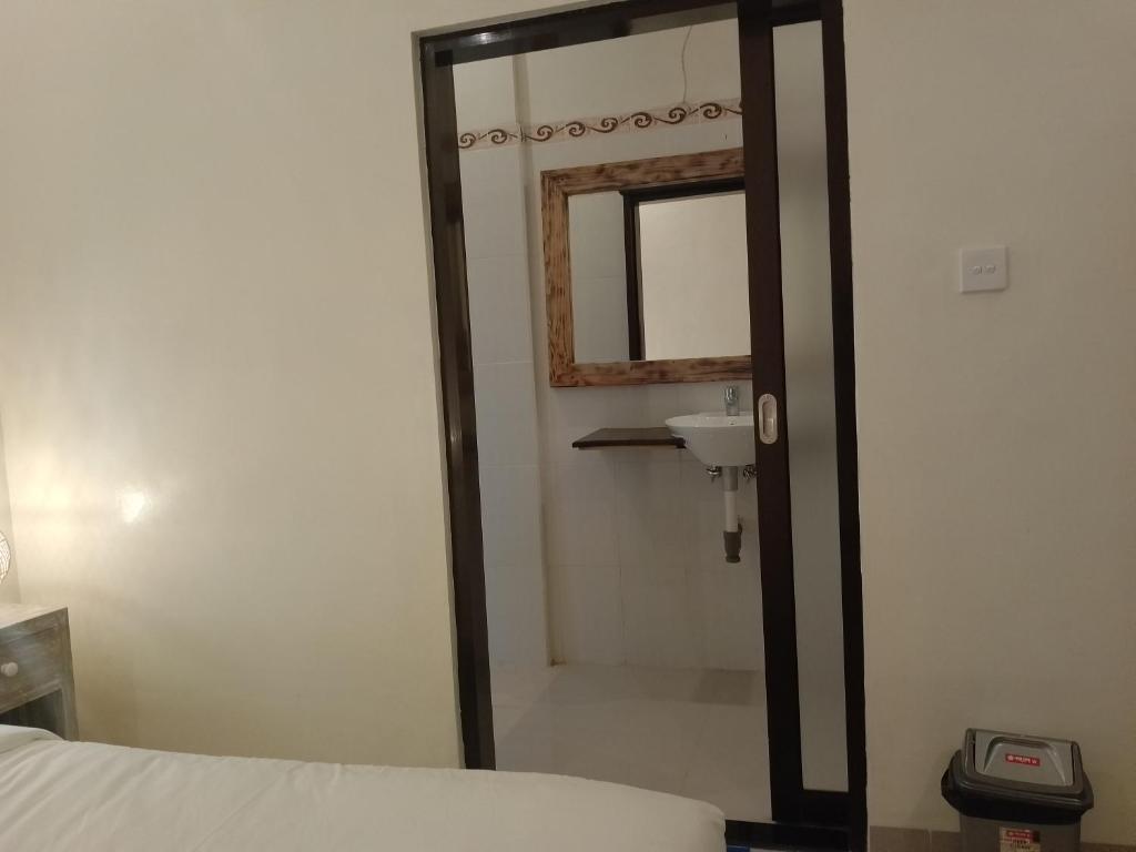 een badkamer met een spiegel, een wastafel en een bed bij Yanti Guest House in Canggu