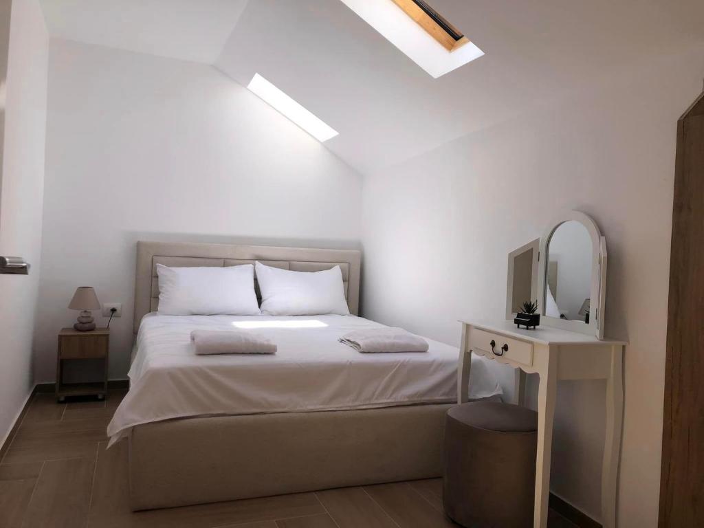 Habitación blanca con cama y espejo en Vila Emante, en Tushemisht