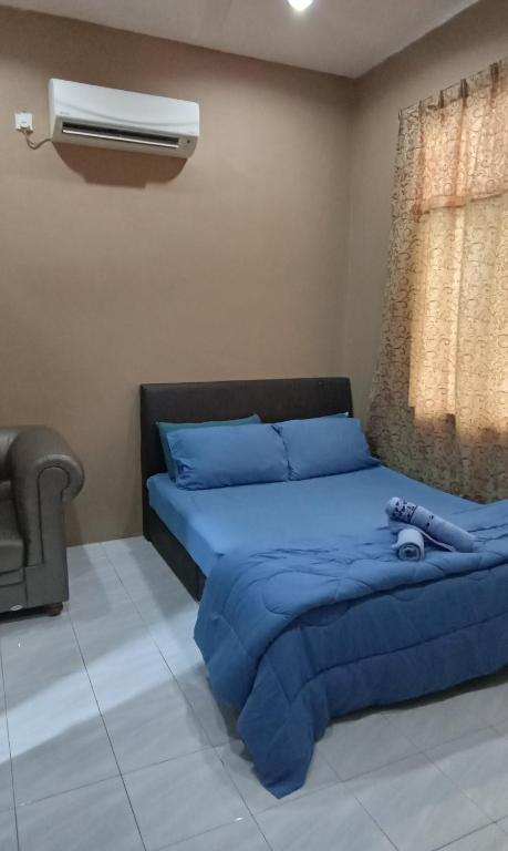 een slaapkamer met een bed met blauwe lakens en een ventilator bij NZ Villa Roomstay in Kangar