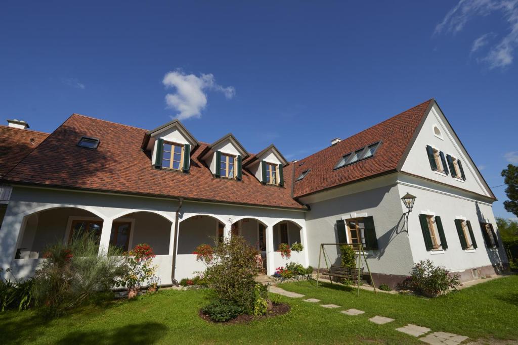 une grande maison blanche avec un toit rouge dans l'établissement Frühstückspension Kleinschuster, à Burgau