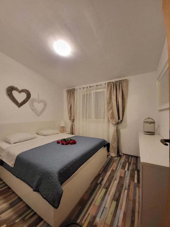 Apartman Roko في سلاتين: غرفة نوم مع سرير بقلبين على الحائط