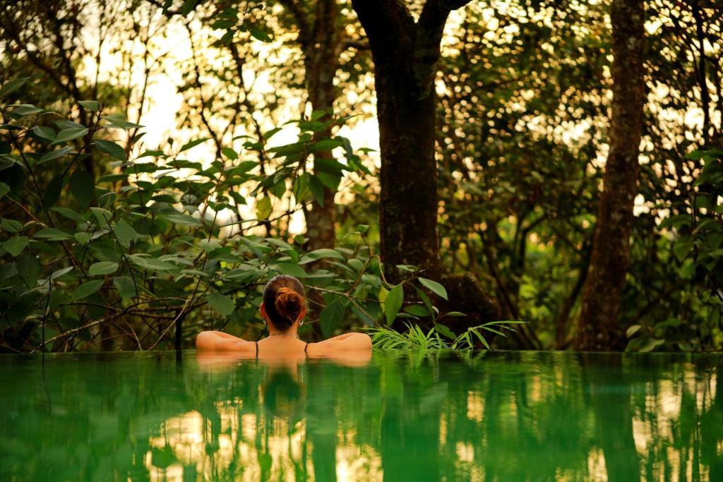 a woman in a pool of water in a forest at Wayanad Wild - Rainforest Lodge by CGH Earth in Vythiri