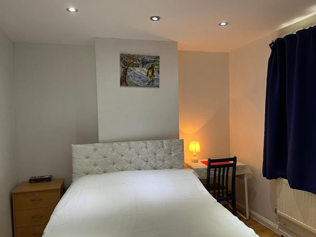 um quarto com uma cama branca e uma secretária com uma cadeira. em Large Double Bedroom with free on site parking em Kingston upon Thames