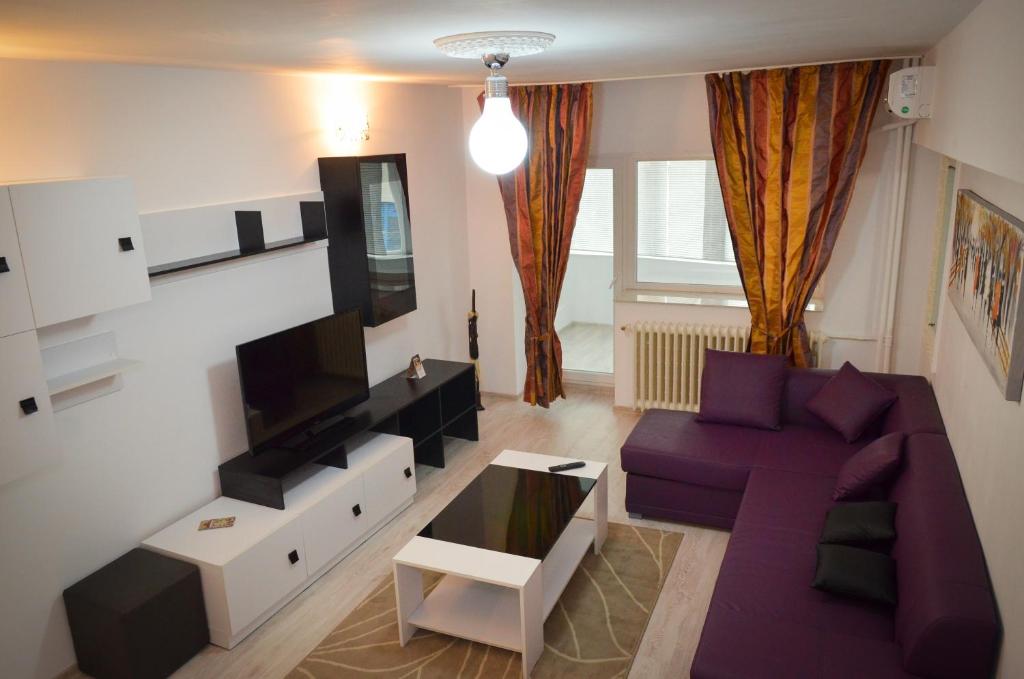 sala de estar con sofá púrpura y TV en Dracula Adventure Tours Accommodation, en Bucarest