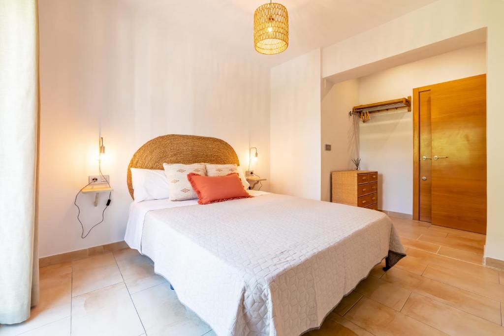 a bedroom with a white bed and a wooden floor at Apartamento Ronda Genil con parking gratuito in Granada