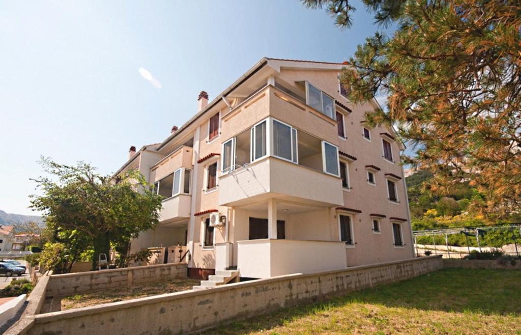 duży biały budynek z drzewami przed nim w obiekcie Apartments with a parking space Baska, Krk - 19443 w Bašce