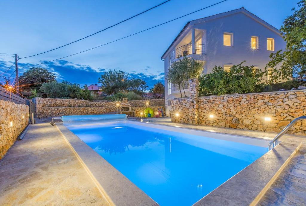 una piscina frente a una casa con una pared de piedra en Family friendly house with a swimming pool Garica, Krk - 19507 en Kras
