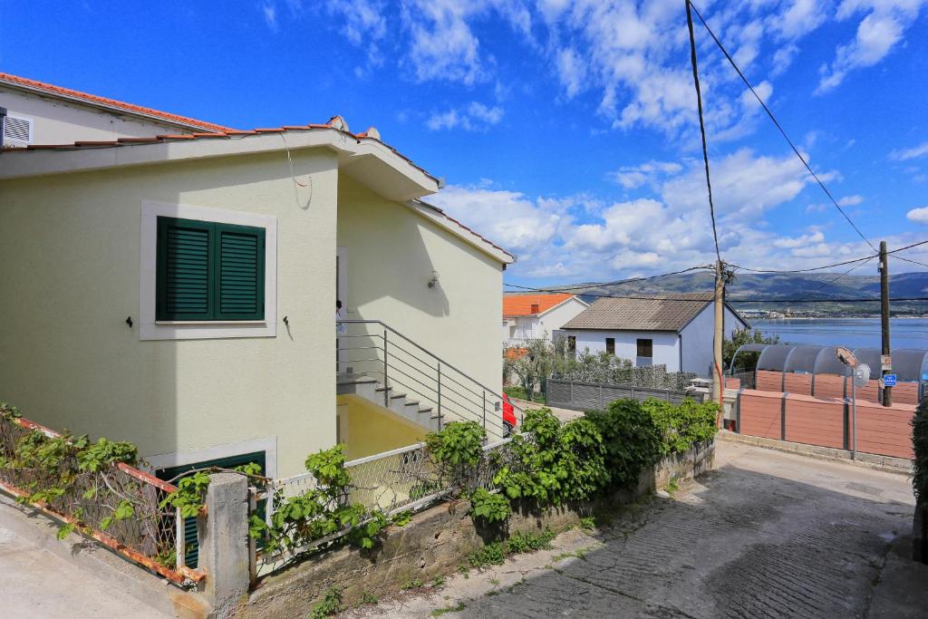 uma casa branca com uma cerca ao lado de uma rua em Apartments by the sea Arbanija, Ciovo - 19576 em Trogir