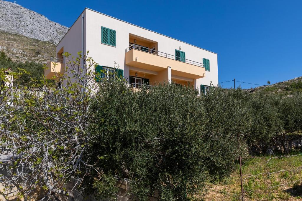 a house on top of a hill with bushes at Apartments with parking space Dugi Rat, Omis - 19516 in Dugi Rat