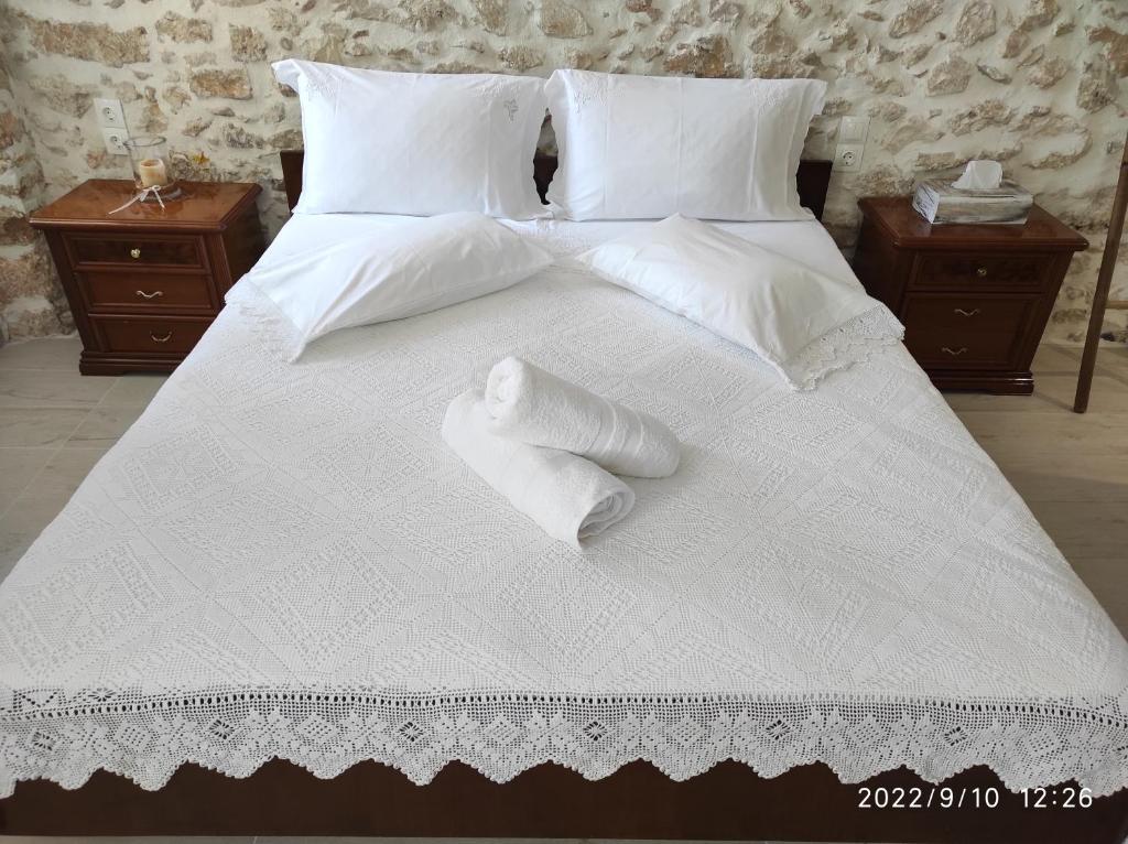 uma grande cama branca com lençóis e almofadas brancos em Xenonas "Alexandra's Coffee House" em Volímai
