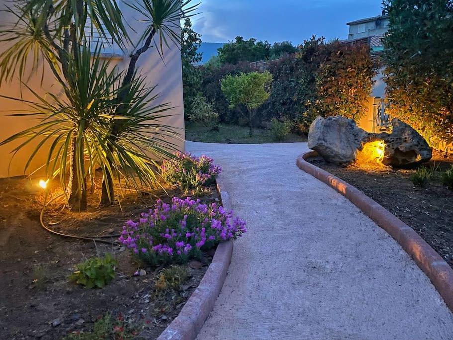 a walkway in a garden with purple flowers at Villa avec piscine privée à Sainte Lucie in Sainte-Lucie de Porto-Vecchio