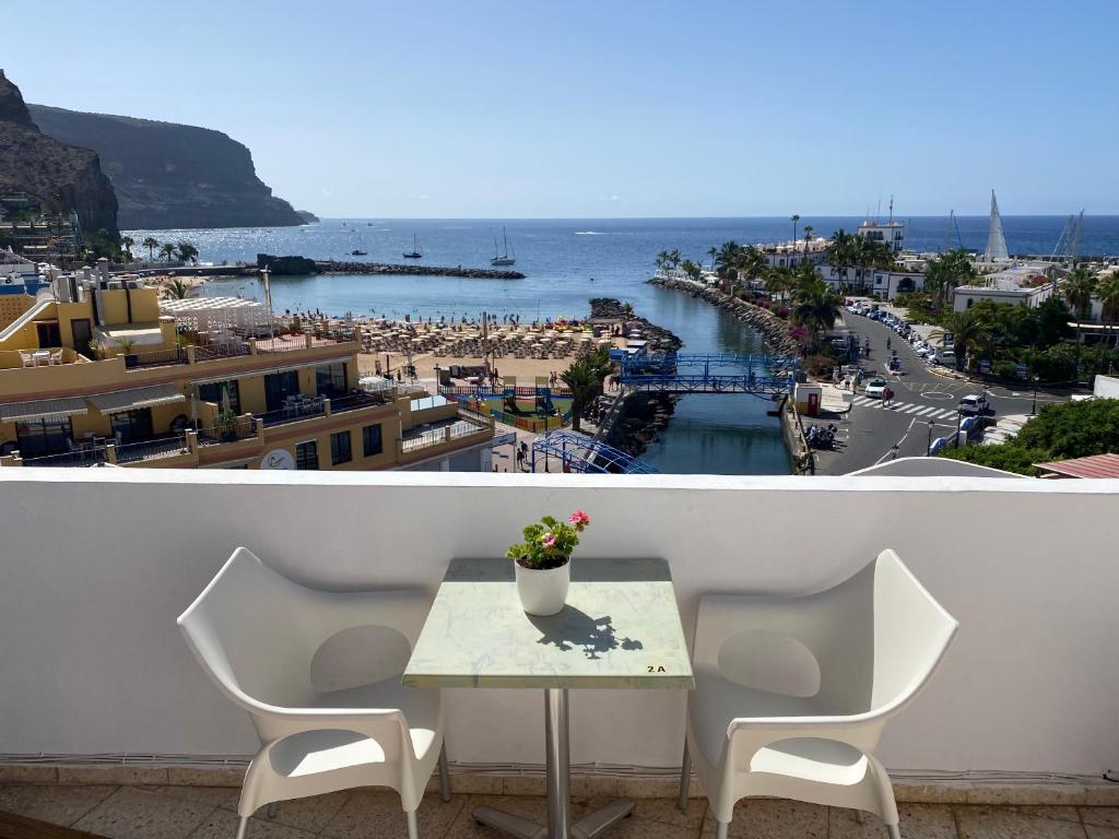 a table and chairs on a balcony with a view of the ocean at Las Brisas Mogan Apartamentos in Puerto de Mogán