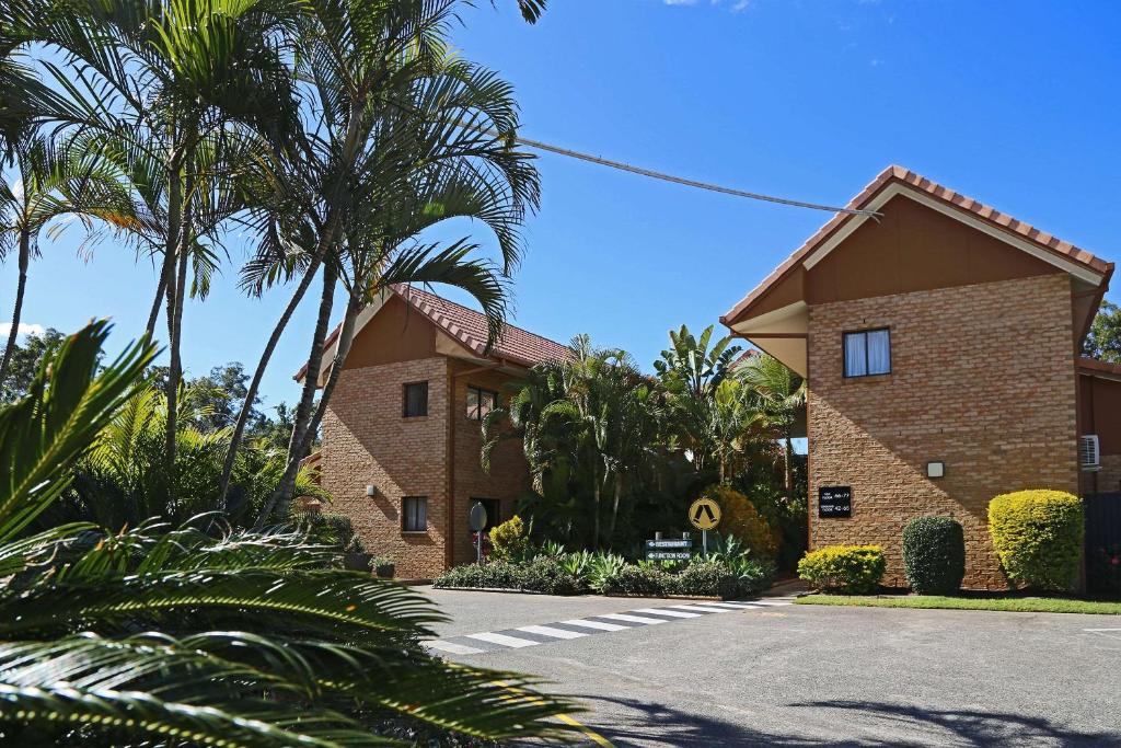 a building with palm trees in front of a street at Quality Hotel Robertson Gardens in Brisbane