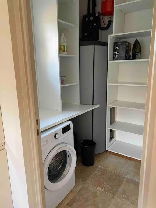 a laundry room with a washing machine and shelves at Villa avec piscine privée à Sainte Lucie in Sainte-Lucie de Porto-Vecchio