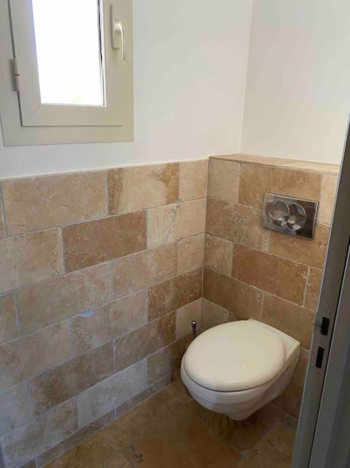 a bathroom with a toilet and a brick wall at Villa avec piscine privée à Sainte Lucie in Sainte-Lucie de Porto-Vecchio