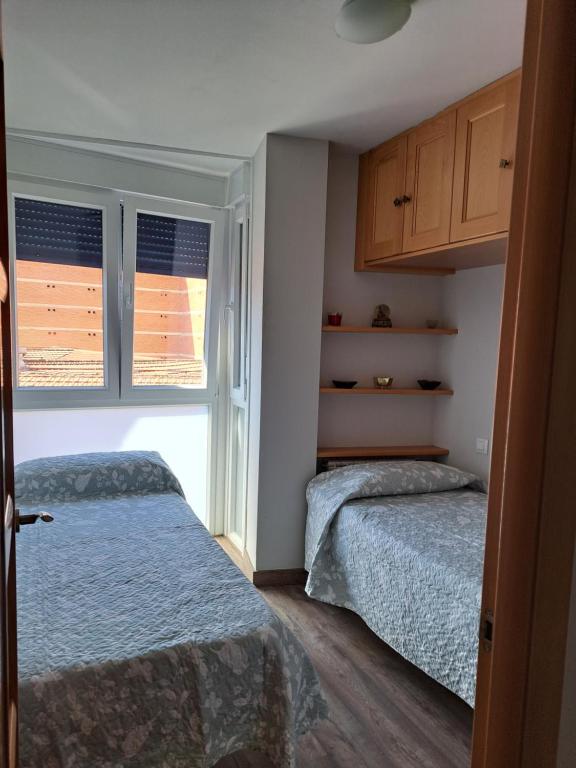 a bedroom with two beds and a window at Tu Morada en Talavera in Talavera de la Reina