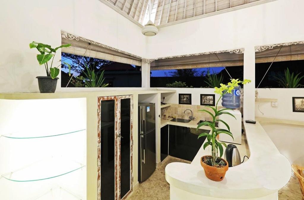 a kitchen with white walls and a table with a plant at Blue Lagoon Apartment 3br in Kuta