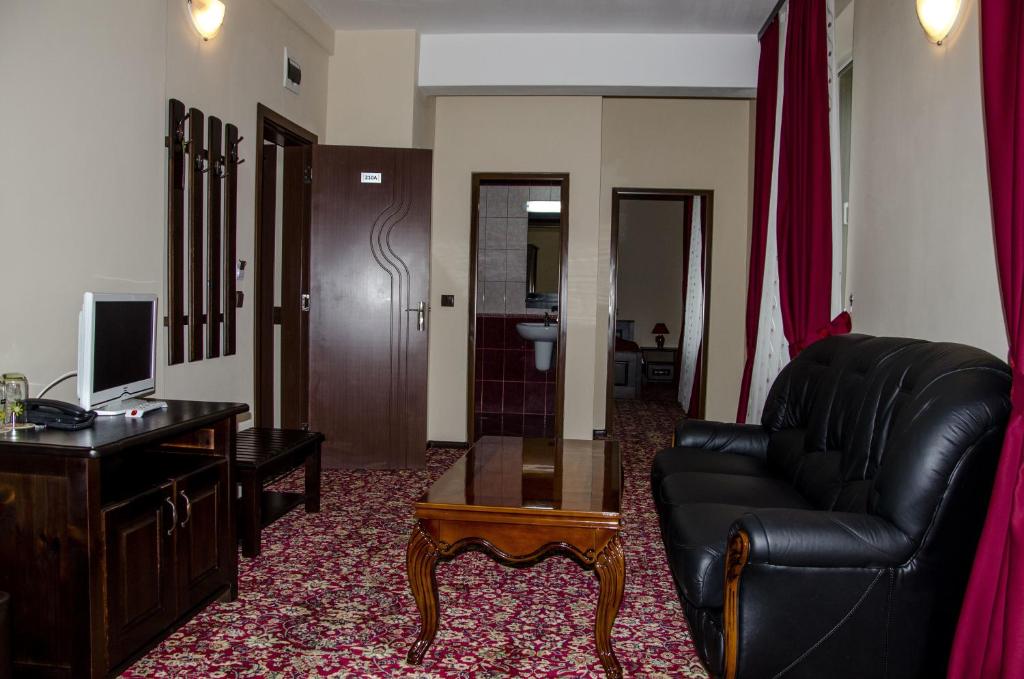a living room with a black leather couch and a desk at Rubis Hotel in Rudozem