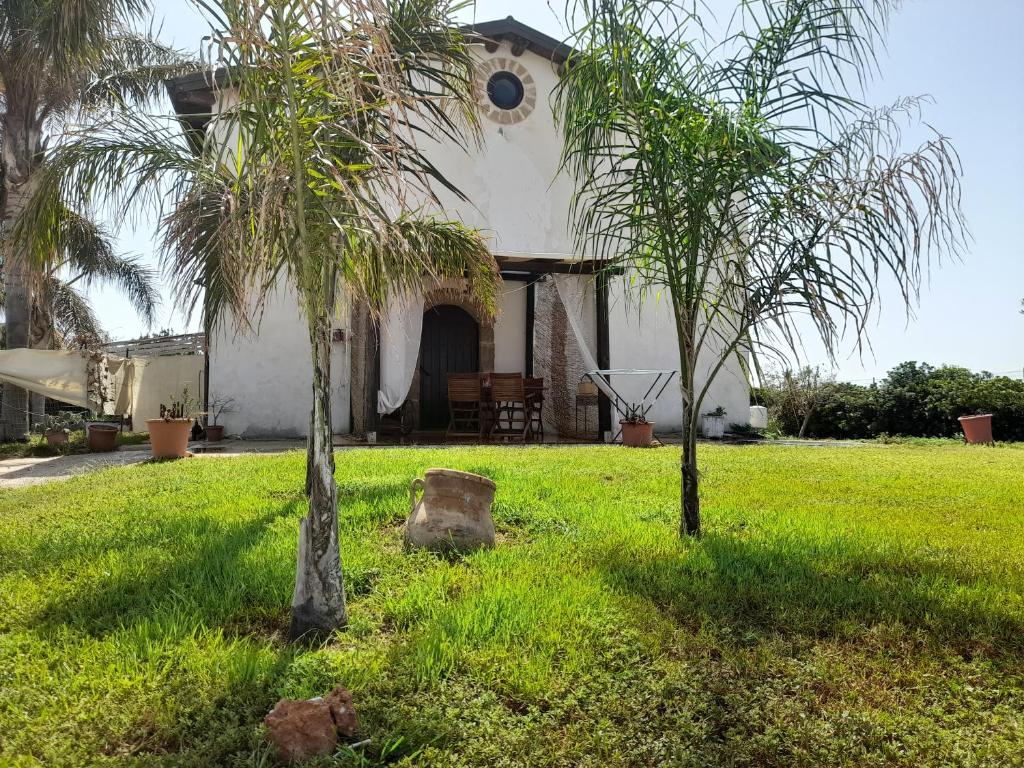 a house with two palm trees in the yard at La casetta di Tina in Marzamemi