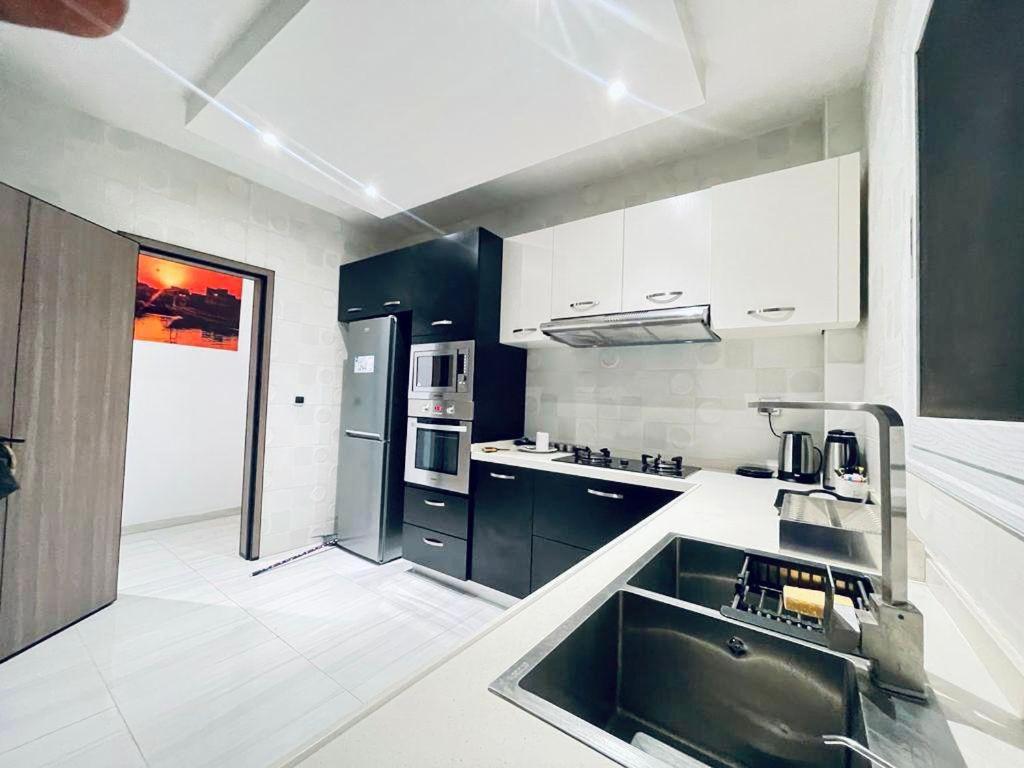 a kitchen with black and white cabinets and a sink at Beau séjour VIP in Dakar