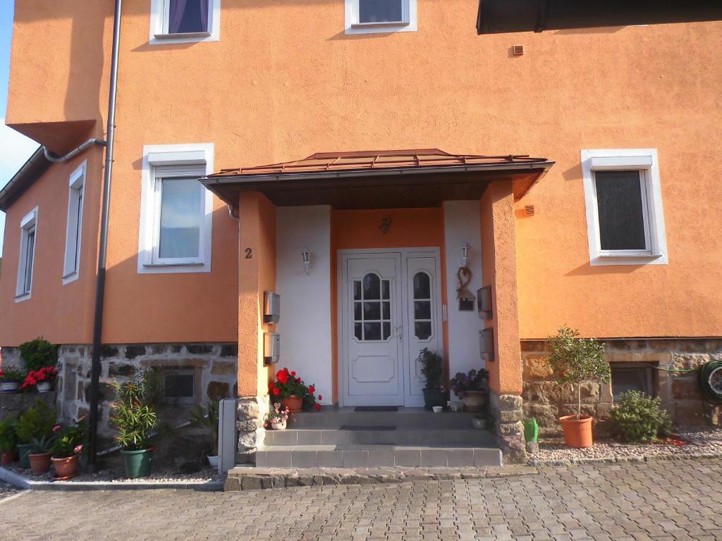 pomarańczowy dom z białymi drzwiami i werandą w obiekcie Ferienwohnung - am- Goethewanderweg w mieście Stützerbach