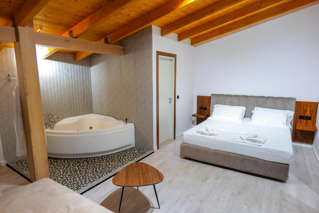a bedroom with a tub and a bed and a table at Hotel Semajo in Vlorë
