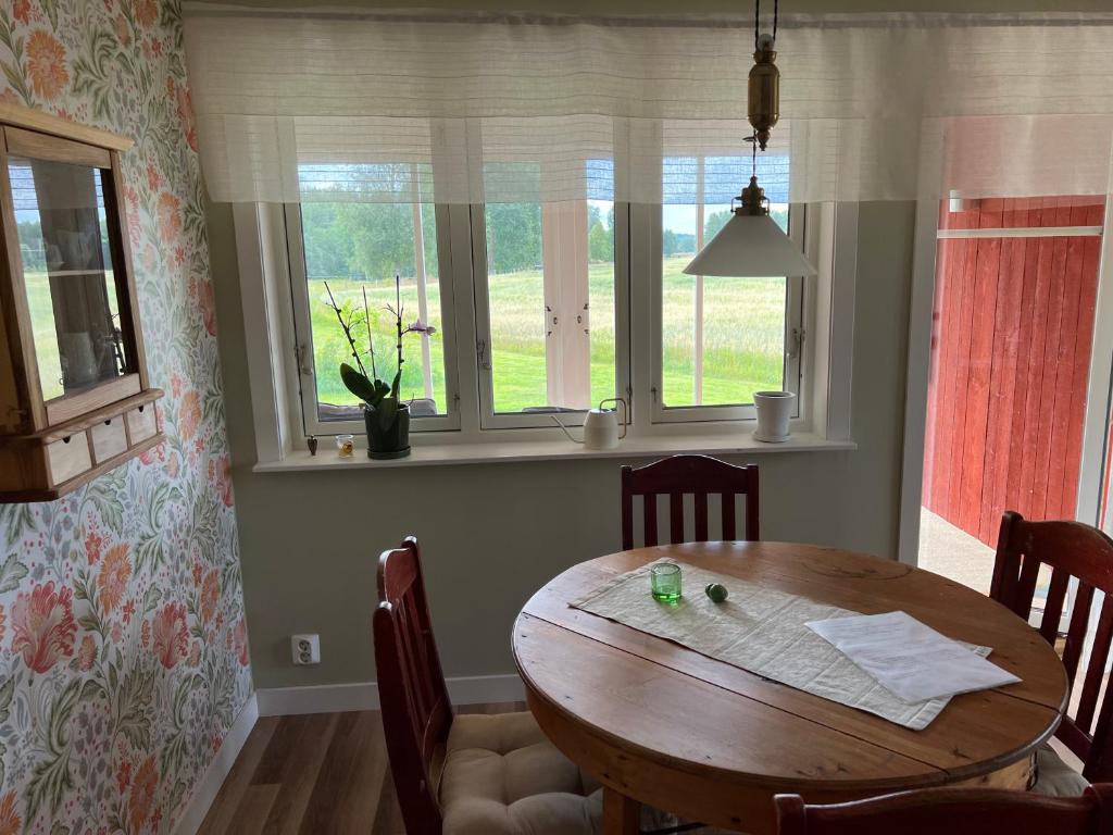 a dining room with a wooden table and windows at Nice apartment, rural idyll just outside Karlstad in Karlstad